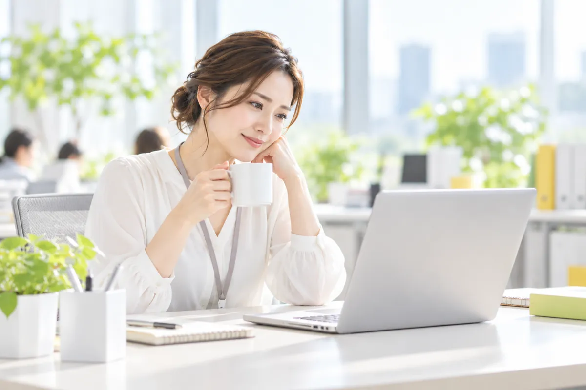 すっきりしたデスクで、コーヒーを手に余裕を持って画面を確認する担当者